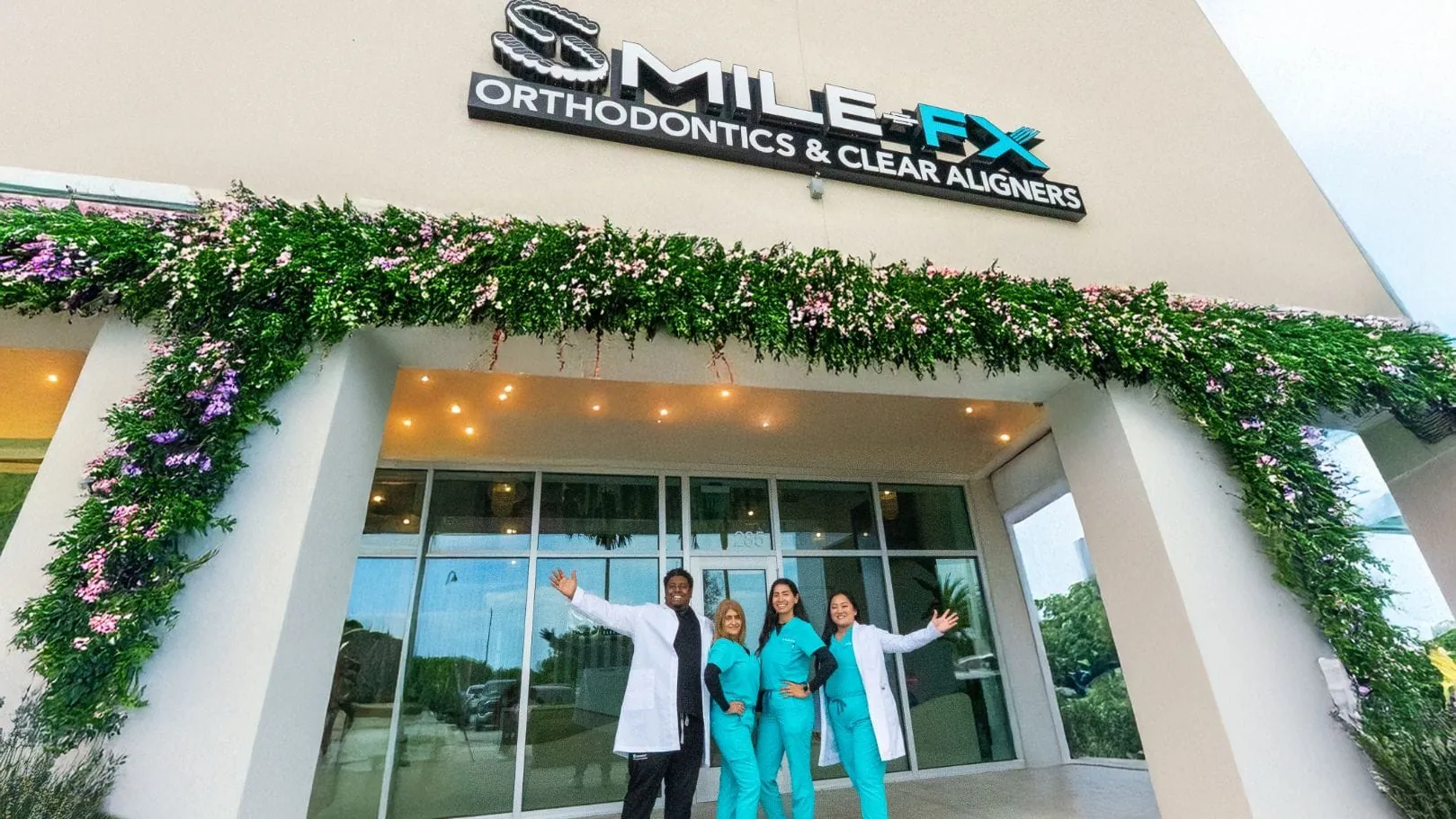 SMILE-FX® sign above the glass entrance, with four people standing outside.